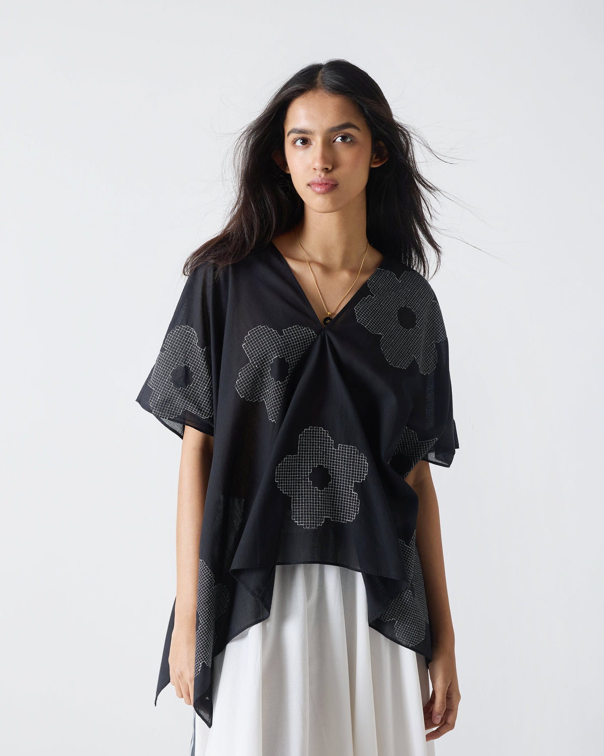 Person wearing a black Curved Hem Top with white flower embroidery.