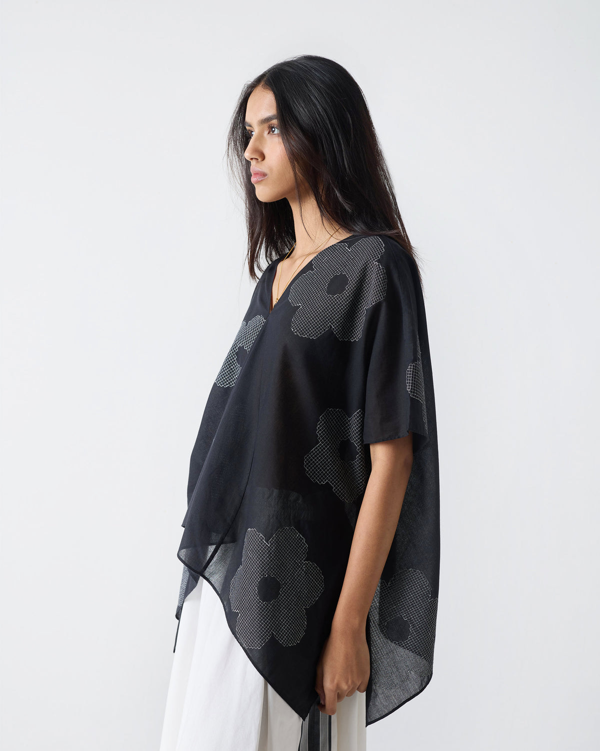 Side view of a black Curved Hem Top with an asymmetrical draped hem.