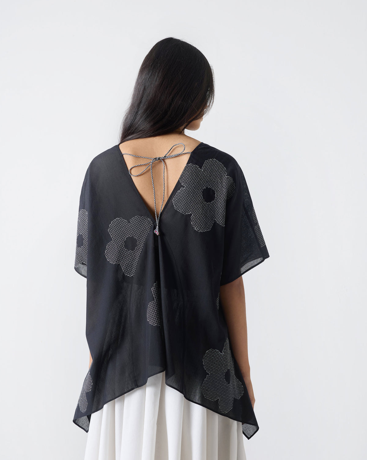 Back of a black Curved Hem Top with a deep V and flower embroidery.
