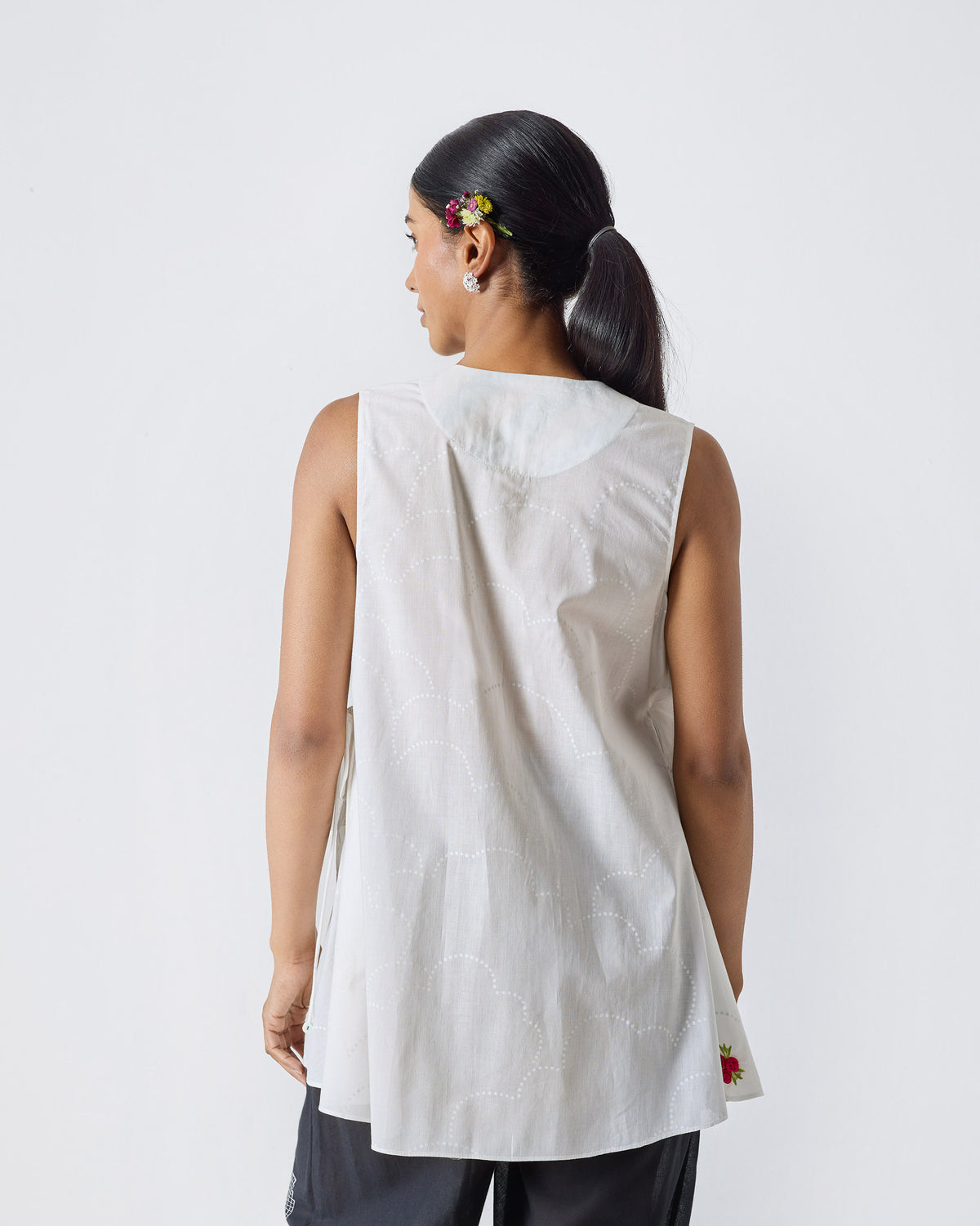 Back of a sleeveless white Ren top worn by a person.