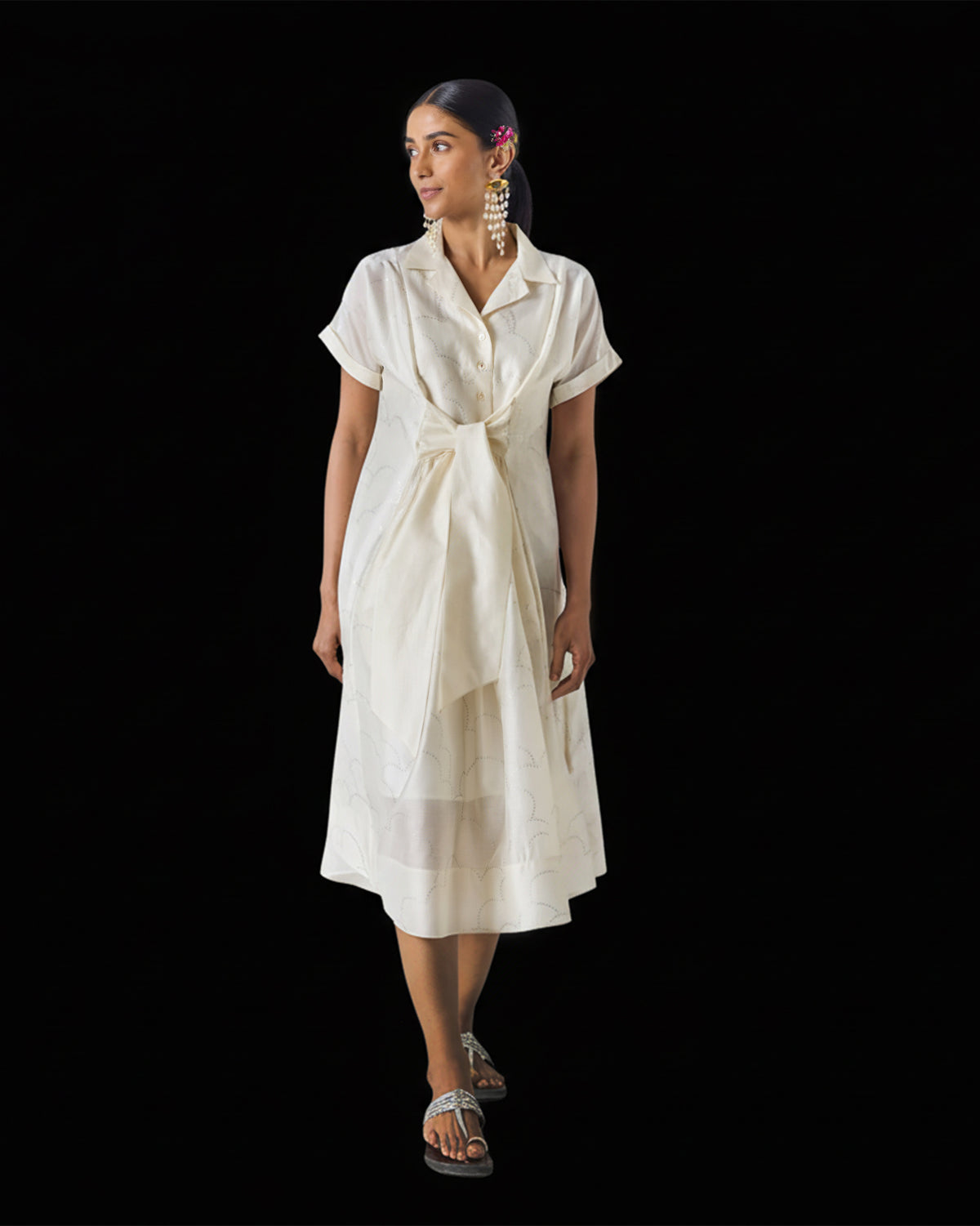 Person wearing an ivory Cadeau Dress with a knotted waist and silver print.