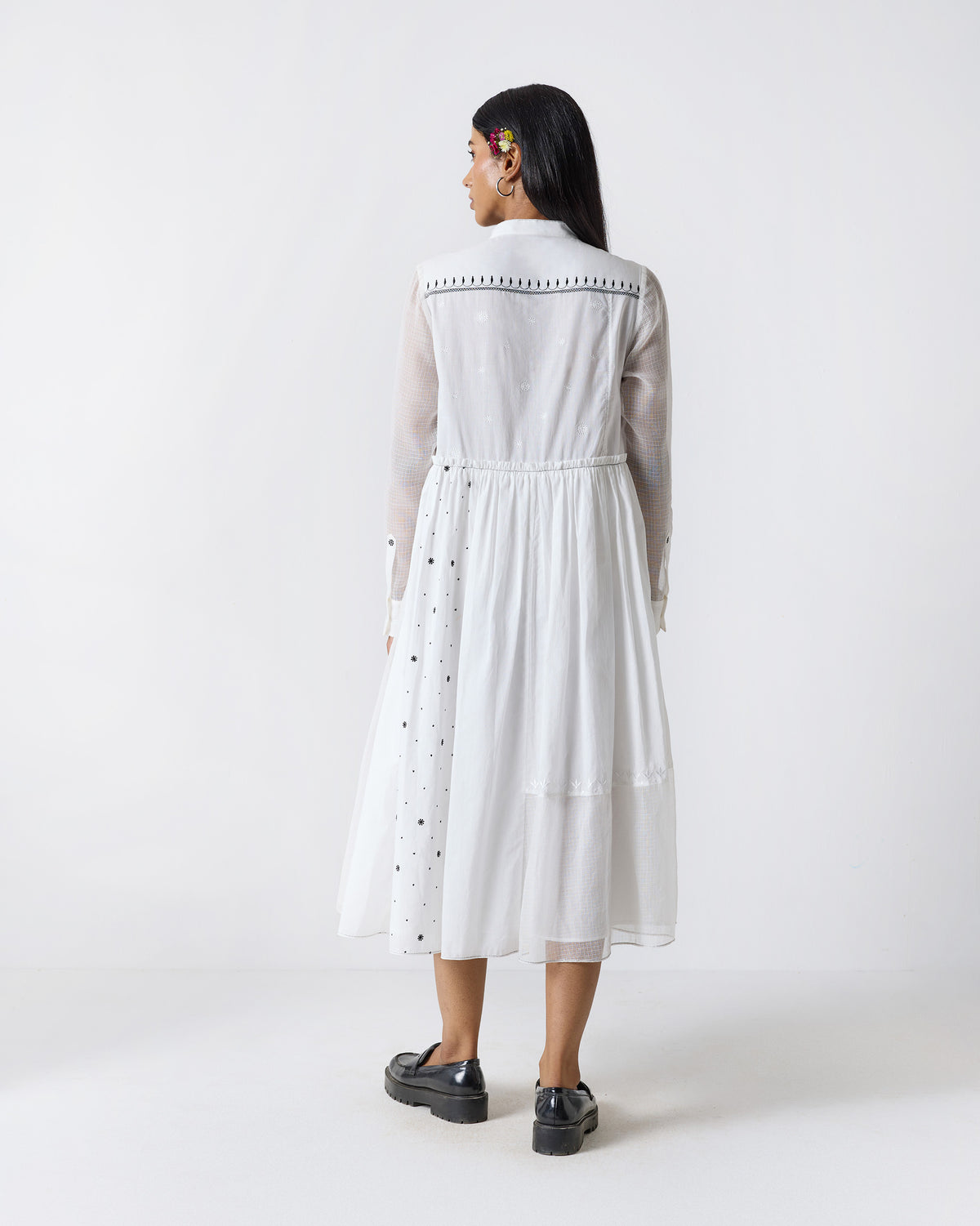 Back of a white Rayna dress showing black yoke embroidery and a gathered midi skirt.