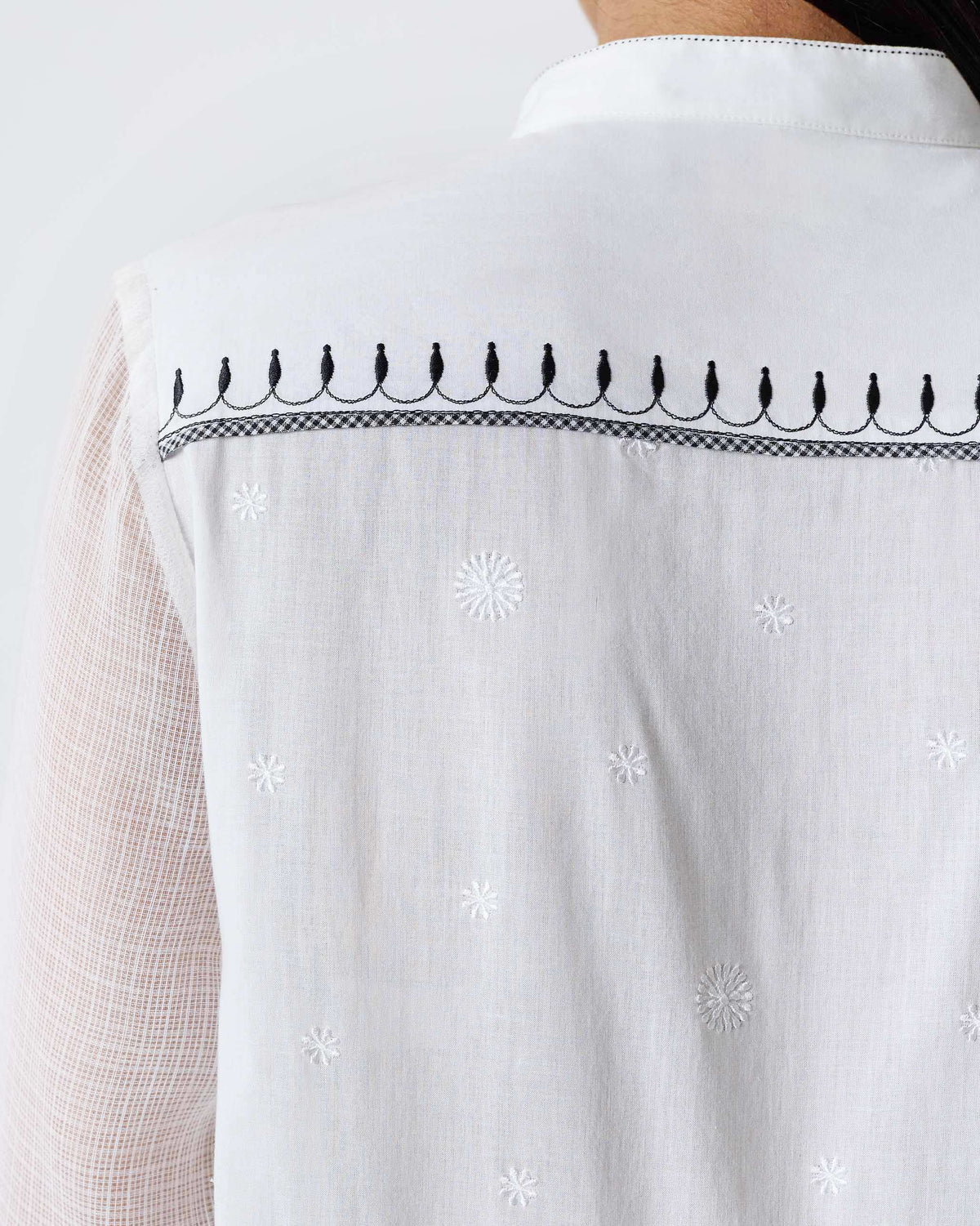 Close-up of black yoke embroidery on the back of a white Rayna dress.