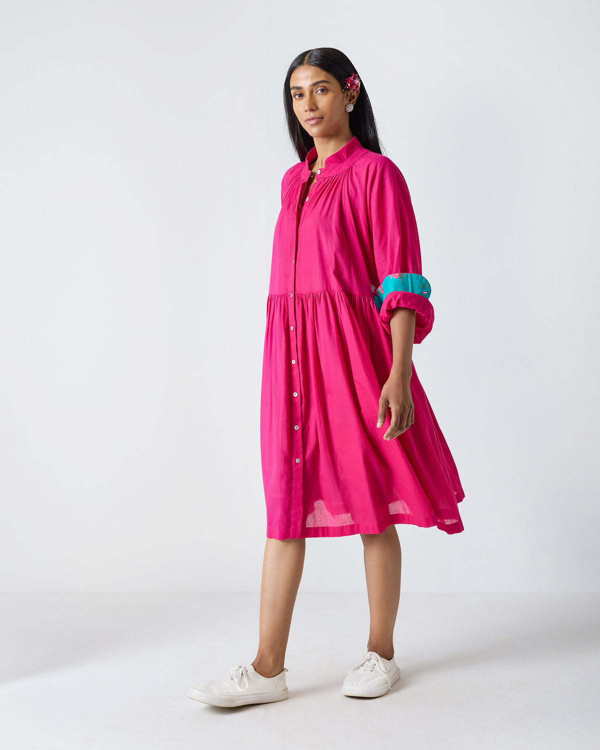 Person wearing a fuchsia Miya dress with turquoise floral sleeve lining.