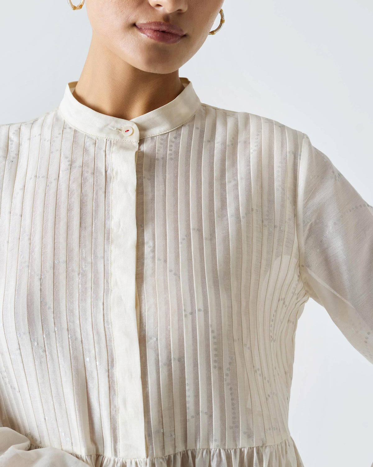 Close-up of an ivory Crescent Pintuck Kurta with pintucks and a fuchsia-stitched button.