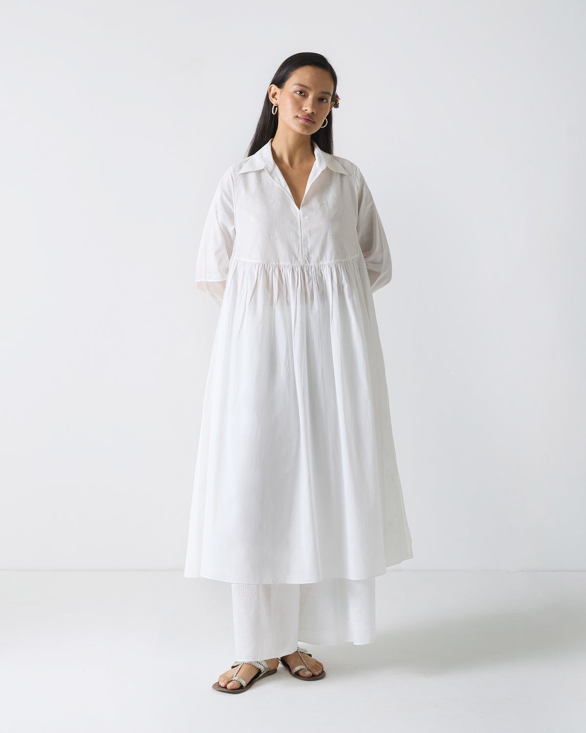 Person wearing a white embroidered kurta with a gathered waist.