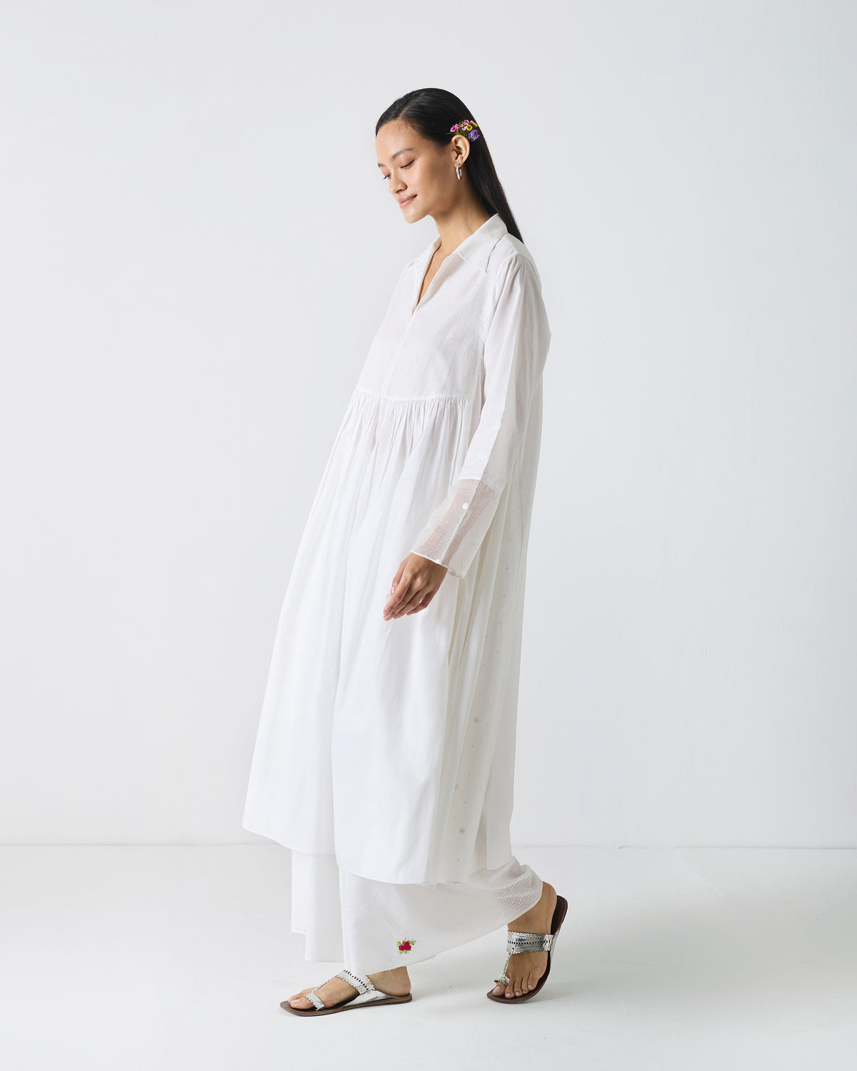 Side view of a long white embroidered kurta worn by a person.
