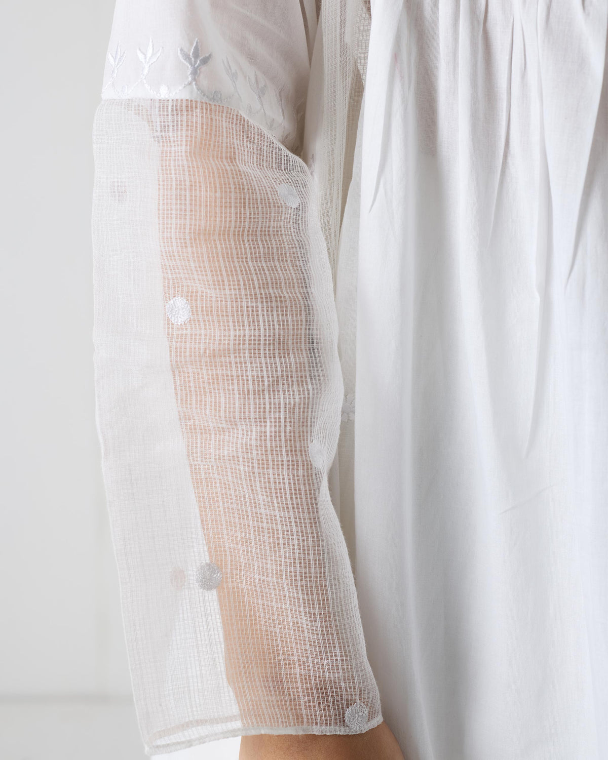 Close-up of a white kurta sleeve with sheer embroidered panel.