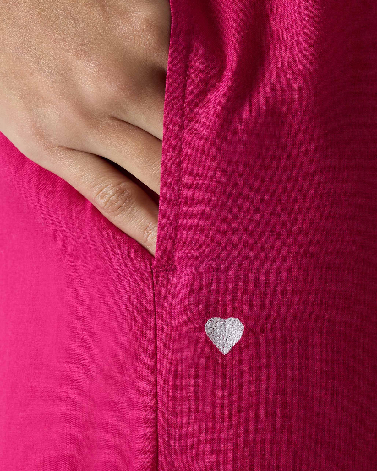 Close-up of a silver heart embroidery on fuchsia Basic Pyjamas.
