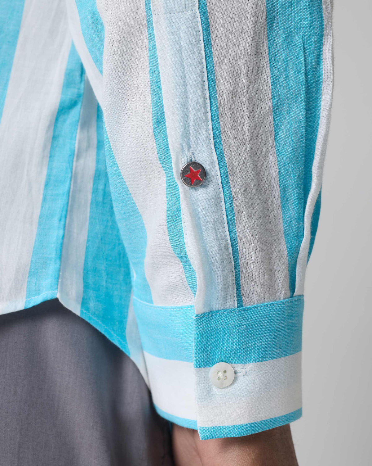 Close-up of a red star button on a blue striped Slim Fit Shirt sleeve.