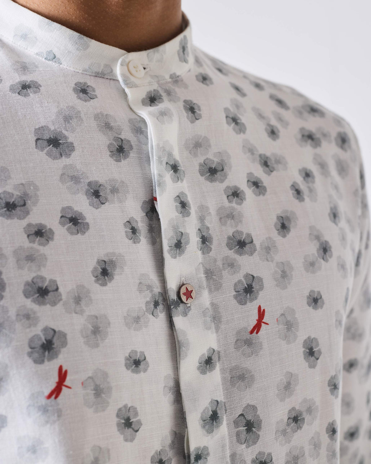 Close-up of a white One Button Shirt showing a red star button and dragonfly print.