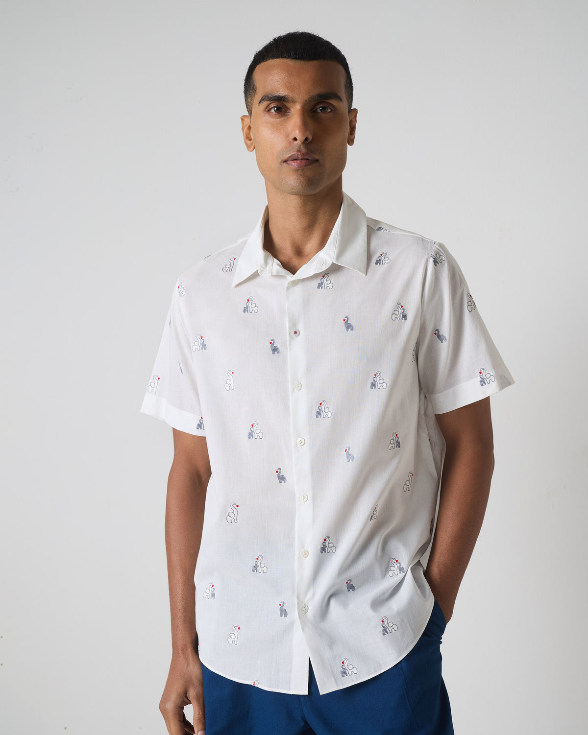 Person wearing a white half sleeves shirt with grey and black embroidered motifs.