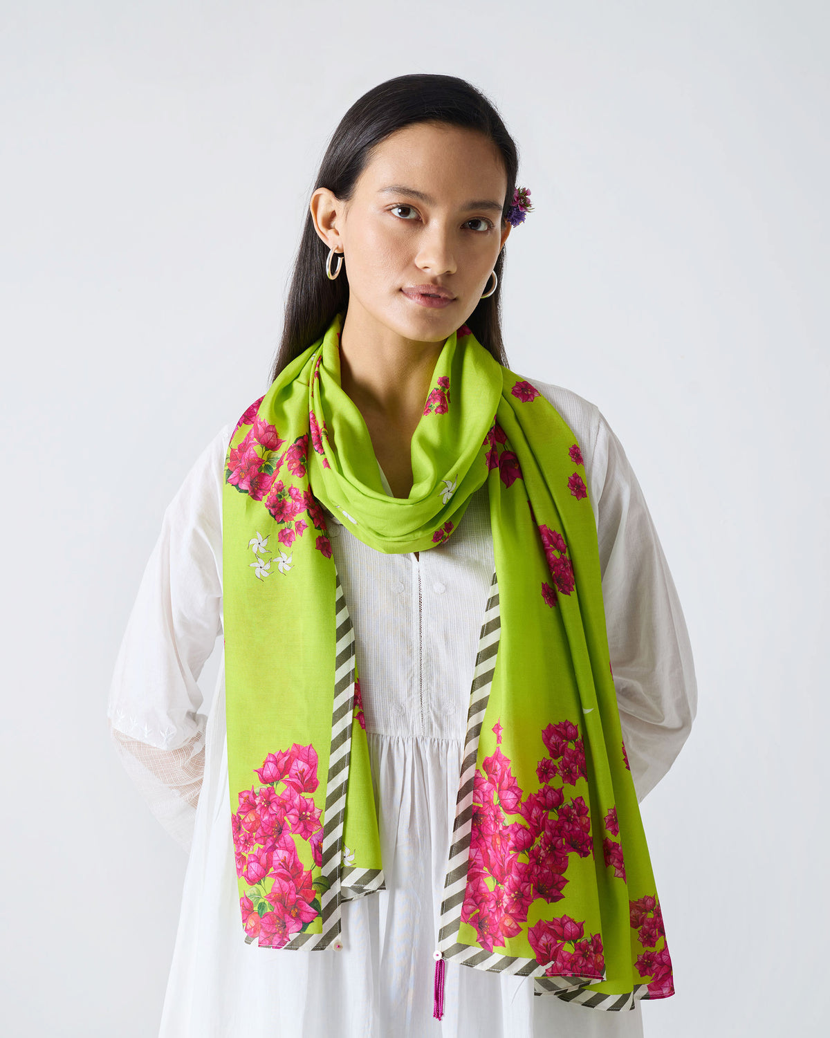 Person wearing the Bougainvillea scarf in lime green with pink blooms and a striped border.
