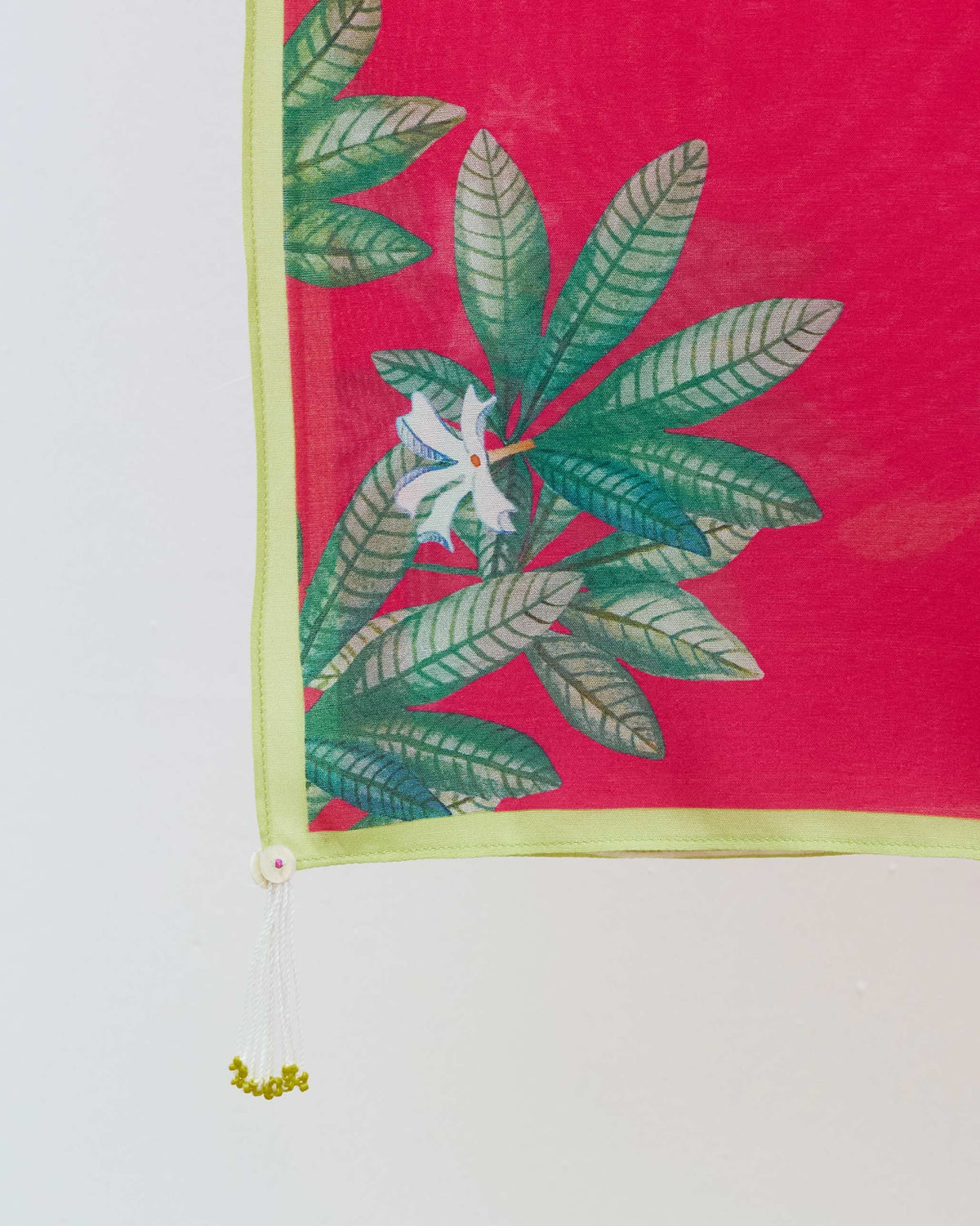 Close-up of a Leaping Fish scarf corner showing green leaves and a white flower.