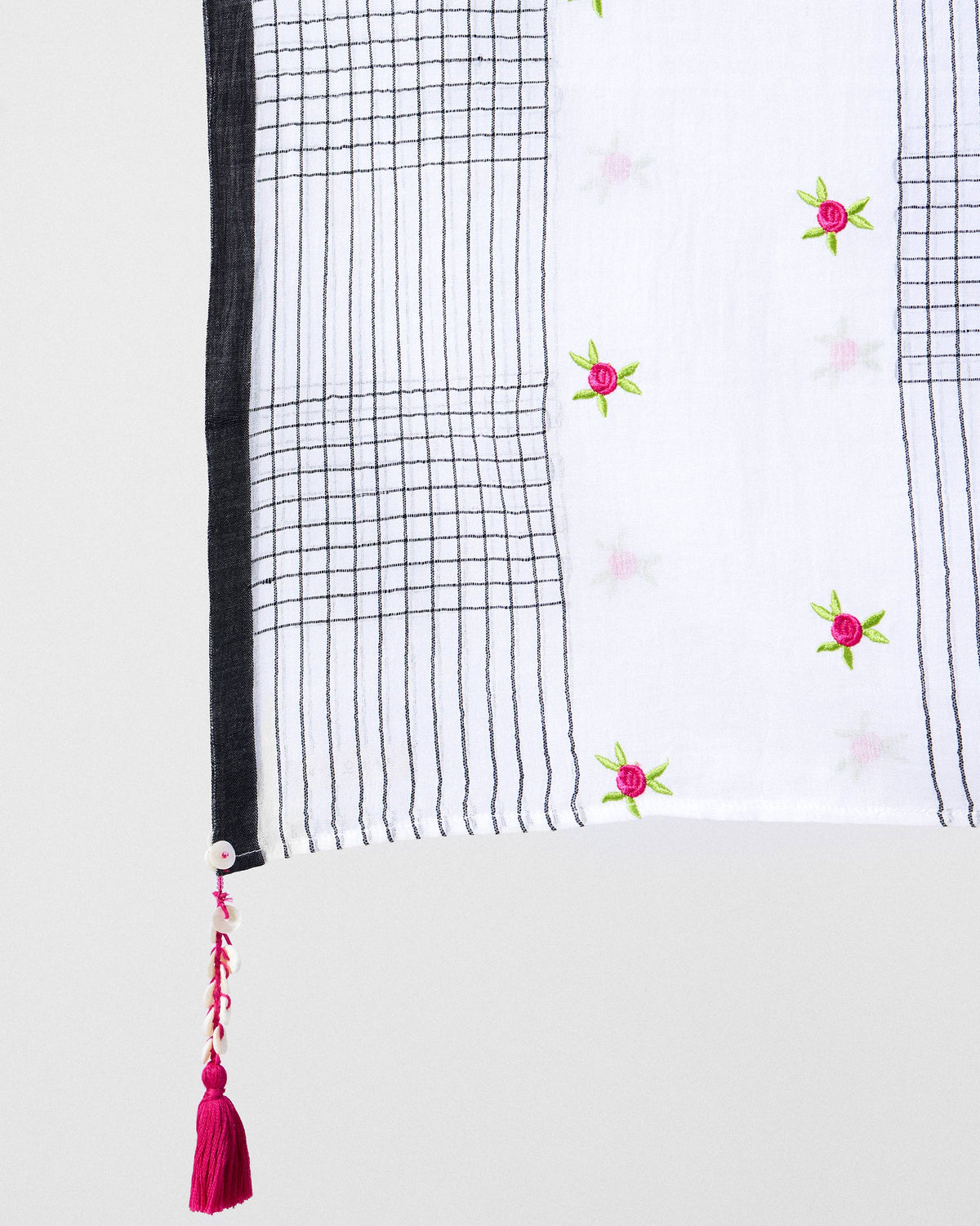 Close-up of Rose Bloom scarf corner showing black grid lines and a pink tassel.