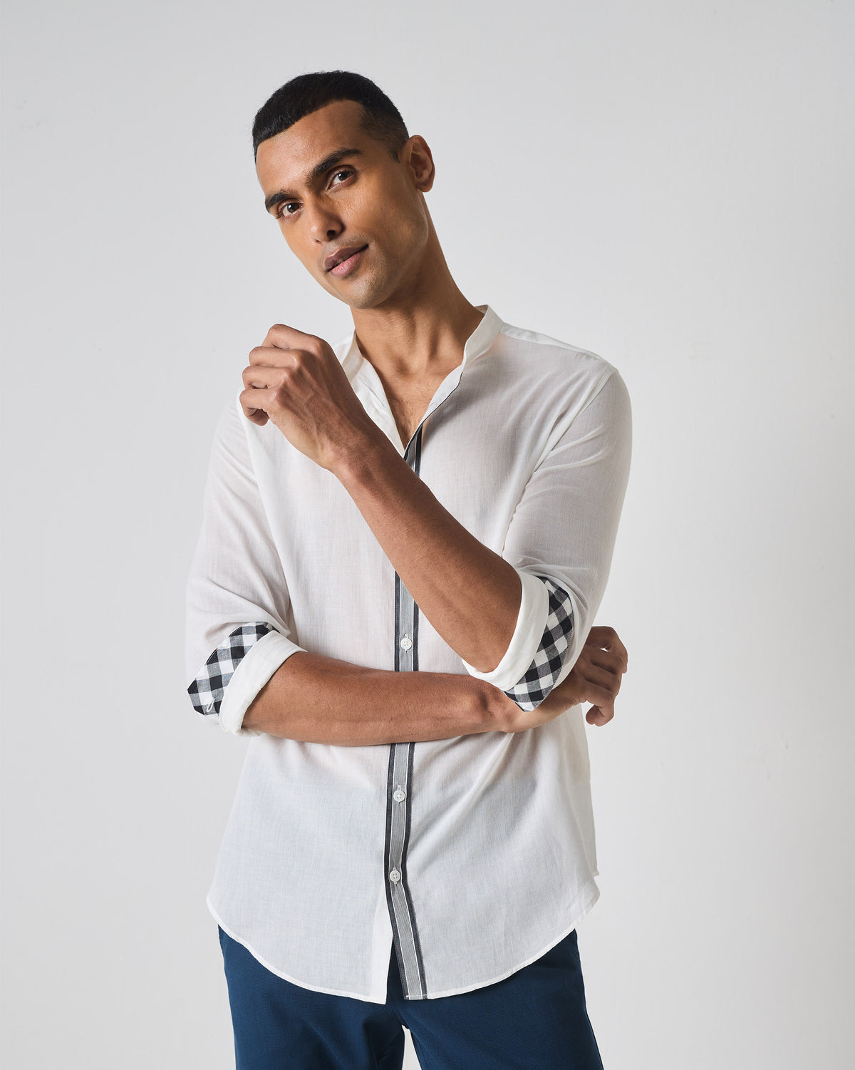 Person wearing a white Neil shirt with striped placket and gingham cuffs.