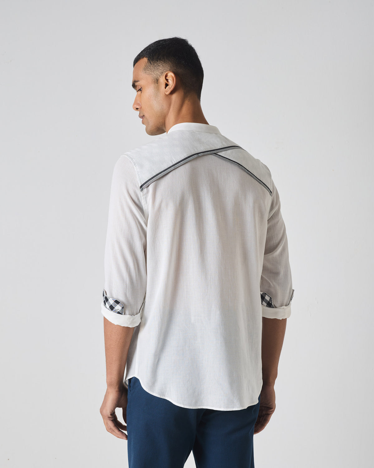 Back of a white Neil shirt with crossed striped piping on the yoke.