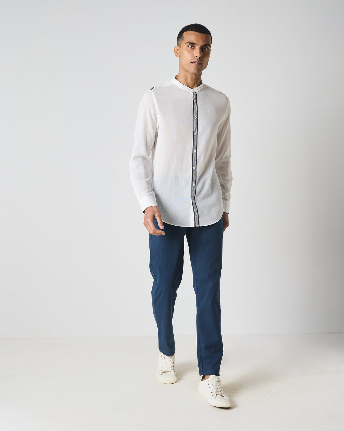Person wearing a white Neil shirt with striped placket trim.