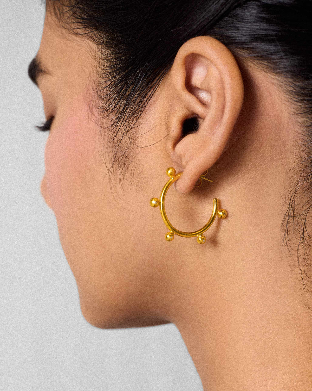 Side profile of a gold Sunshine hoop with bead accents on a person.
