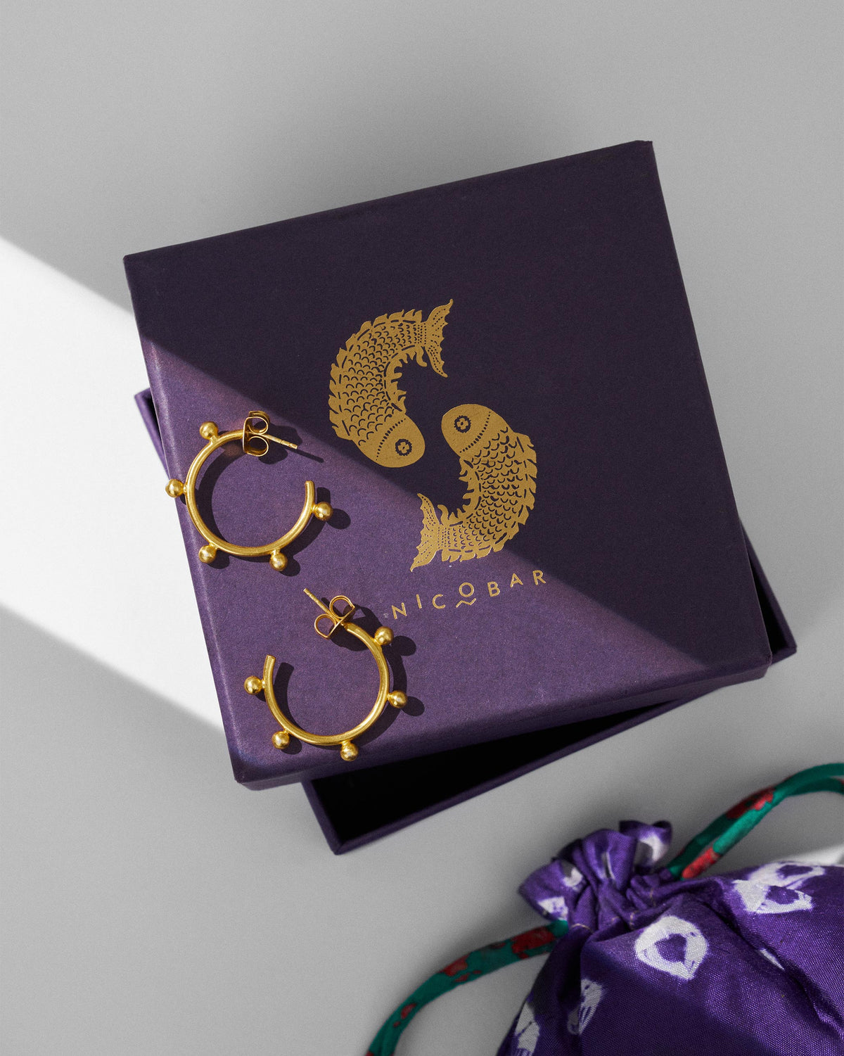 Gold Sunshine hoops on a purple Nicobar gift box.