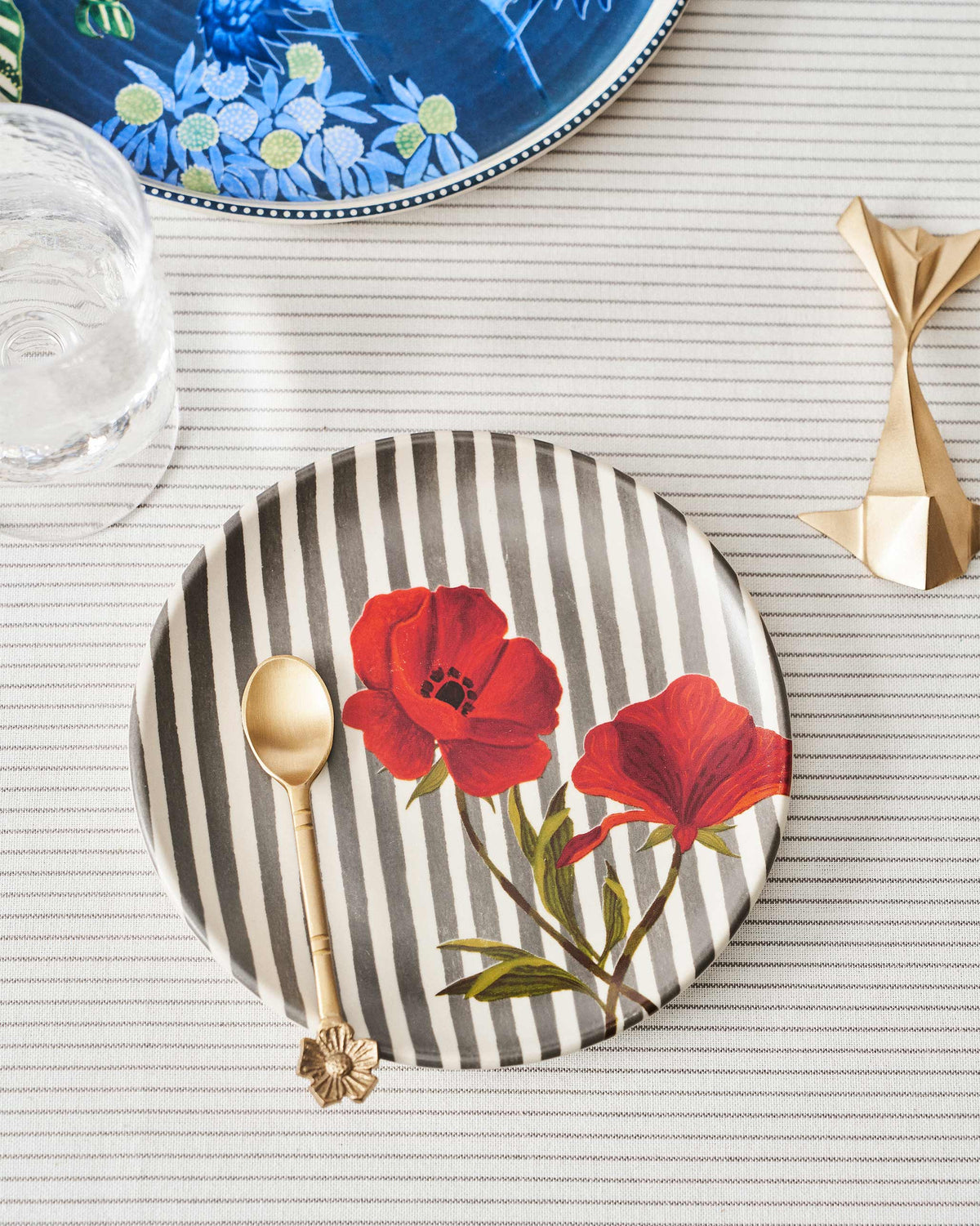 Striped Poppy quarter plate set with a gold spoon on a table.
