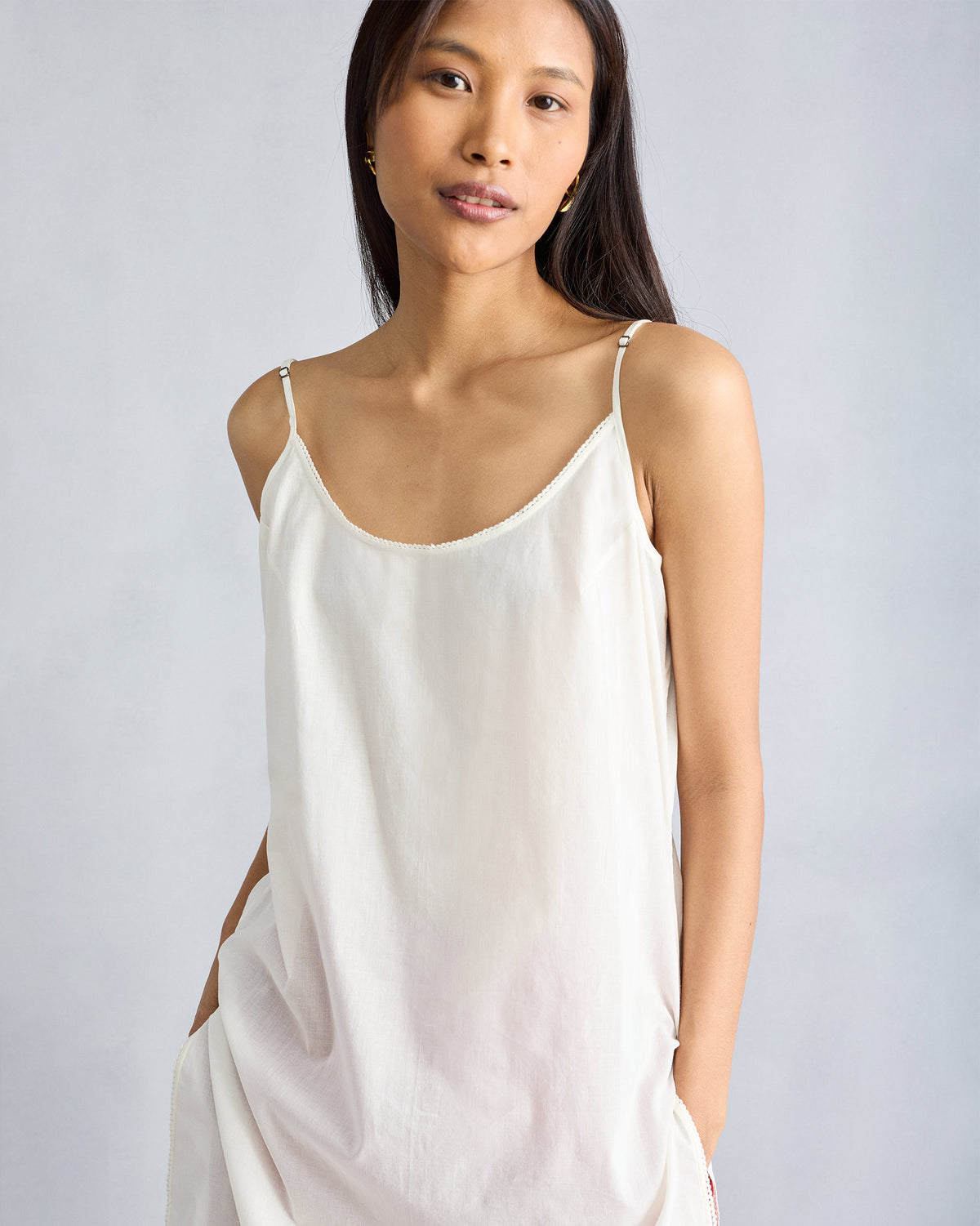 Person wearing an ivory vintage camisole with lace trim and thin straps.