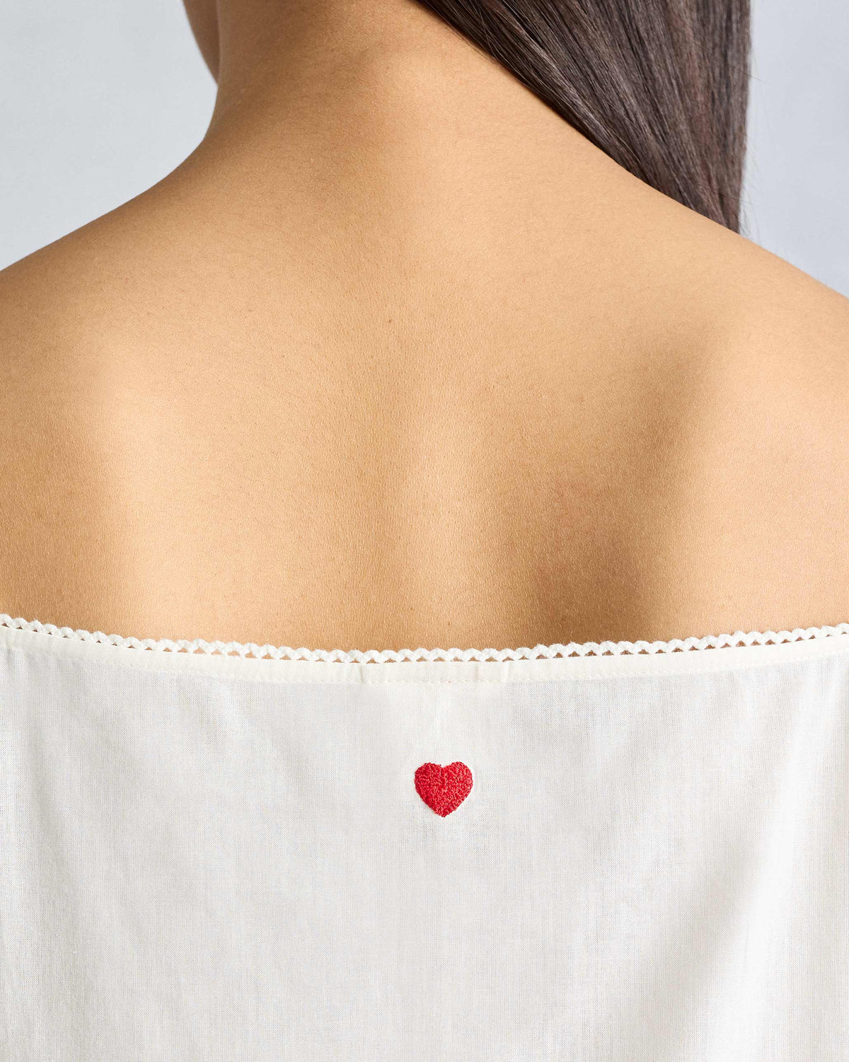 Close-up of a red heart embroidery on an ivory vintage camisole.