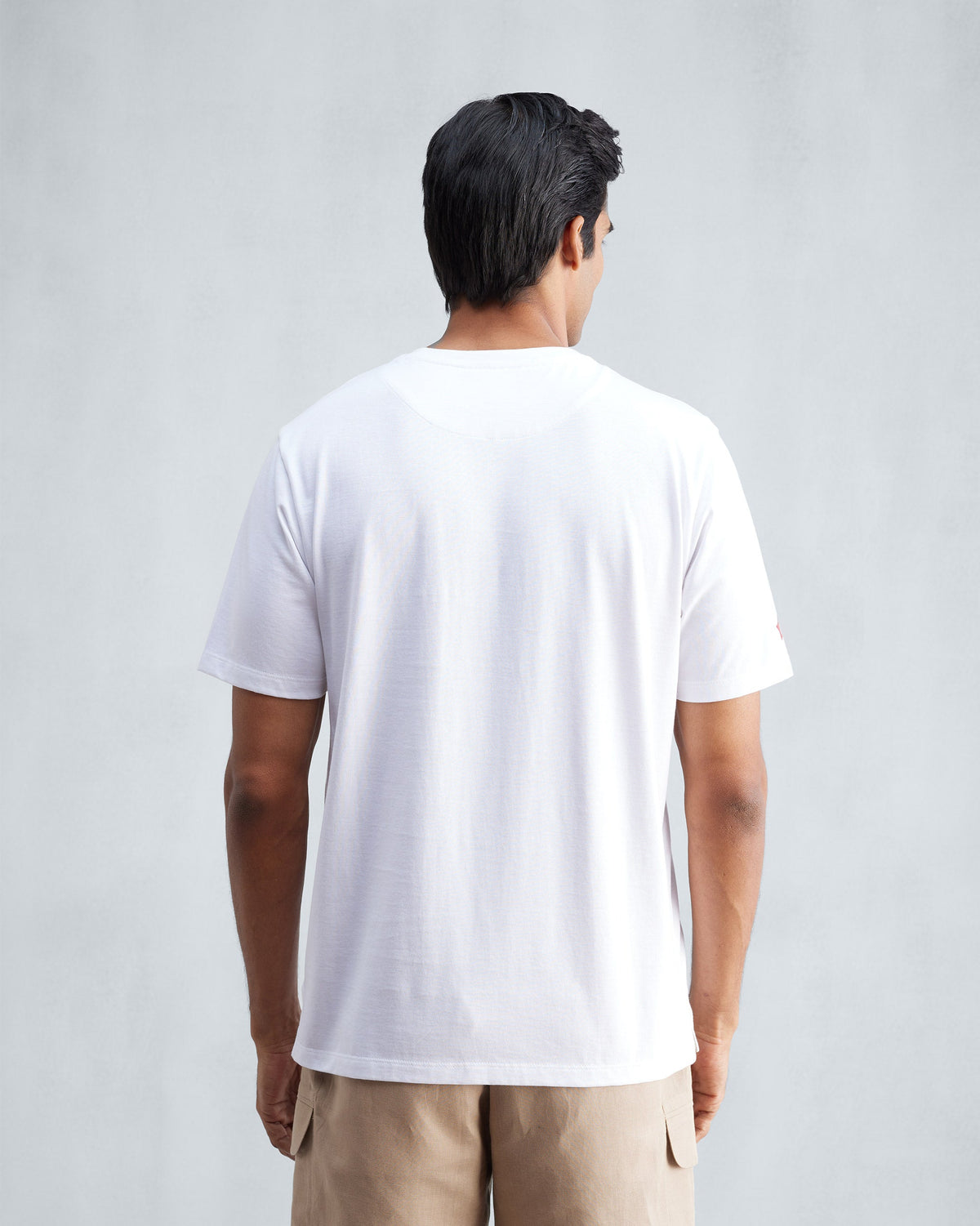 Back of a white Everyday Essentials t-shirt worn by a person.
