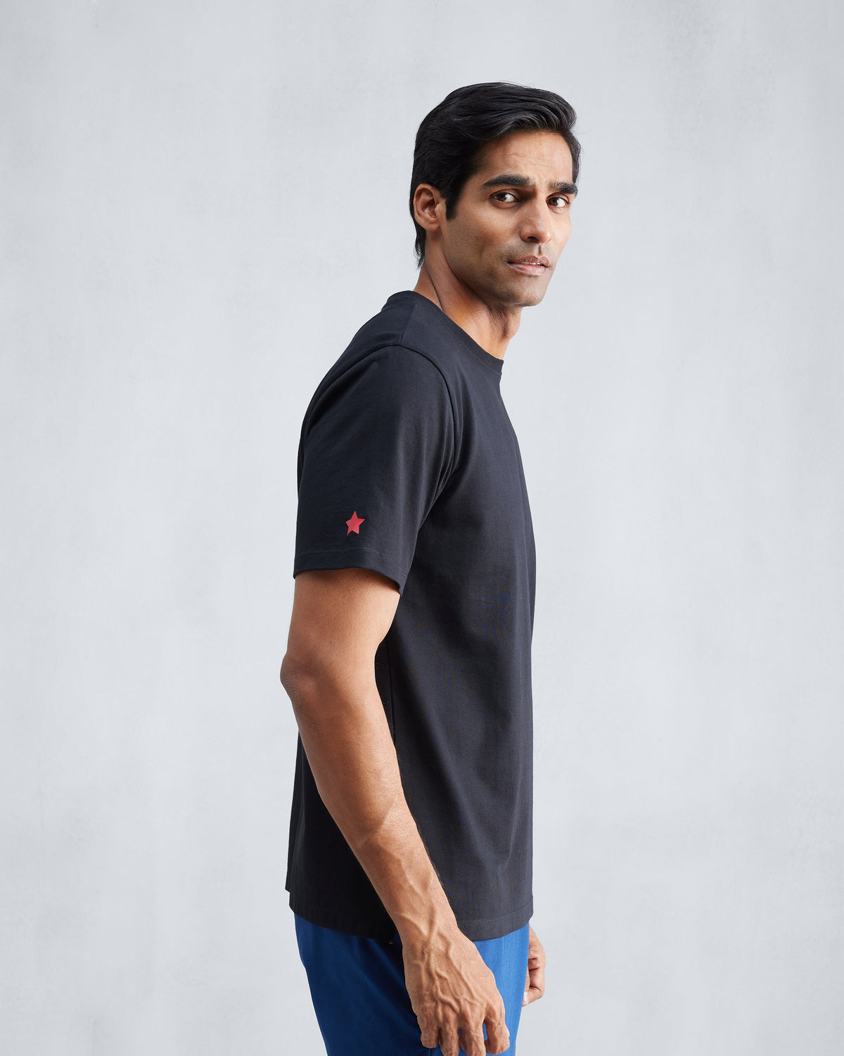 Side view of a black Everyday Essentials t-shirt with a red star.