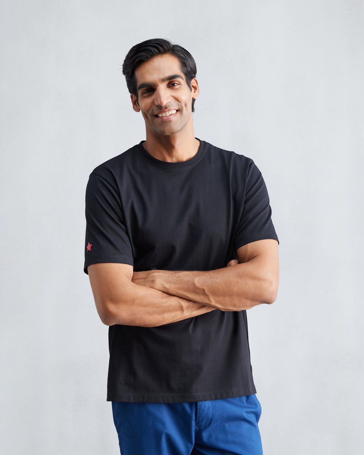 Person wearing a black Everyday Essentials t-shirt with a red star.