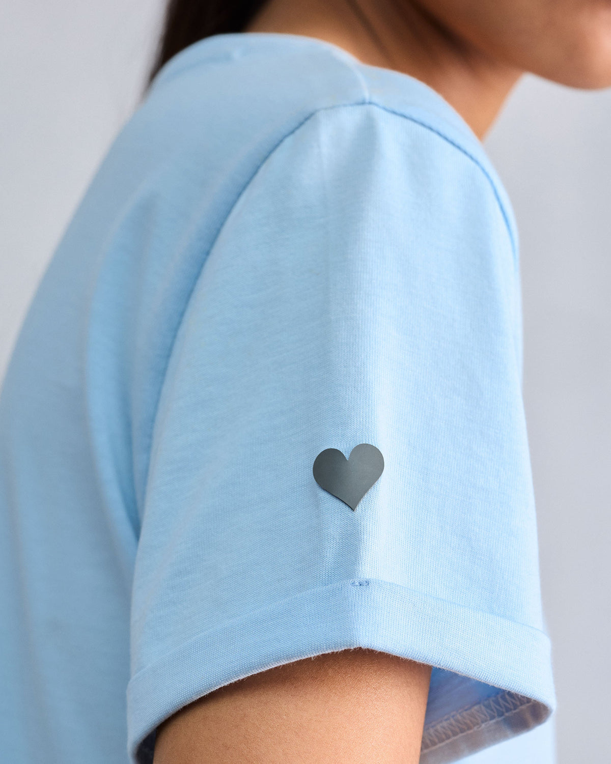 Close-up of a dark heart on a light blue Basic t-shirt sleeve.