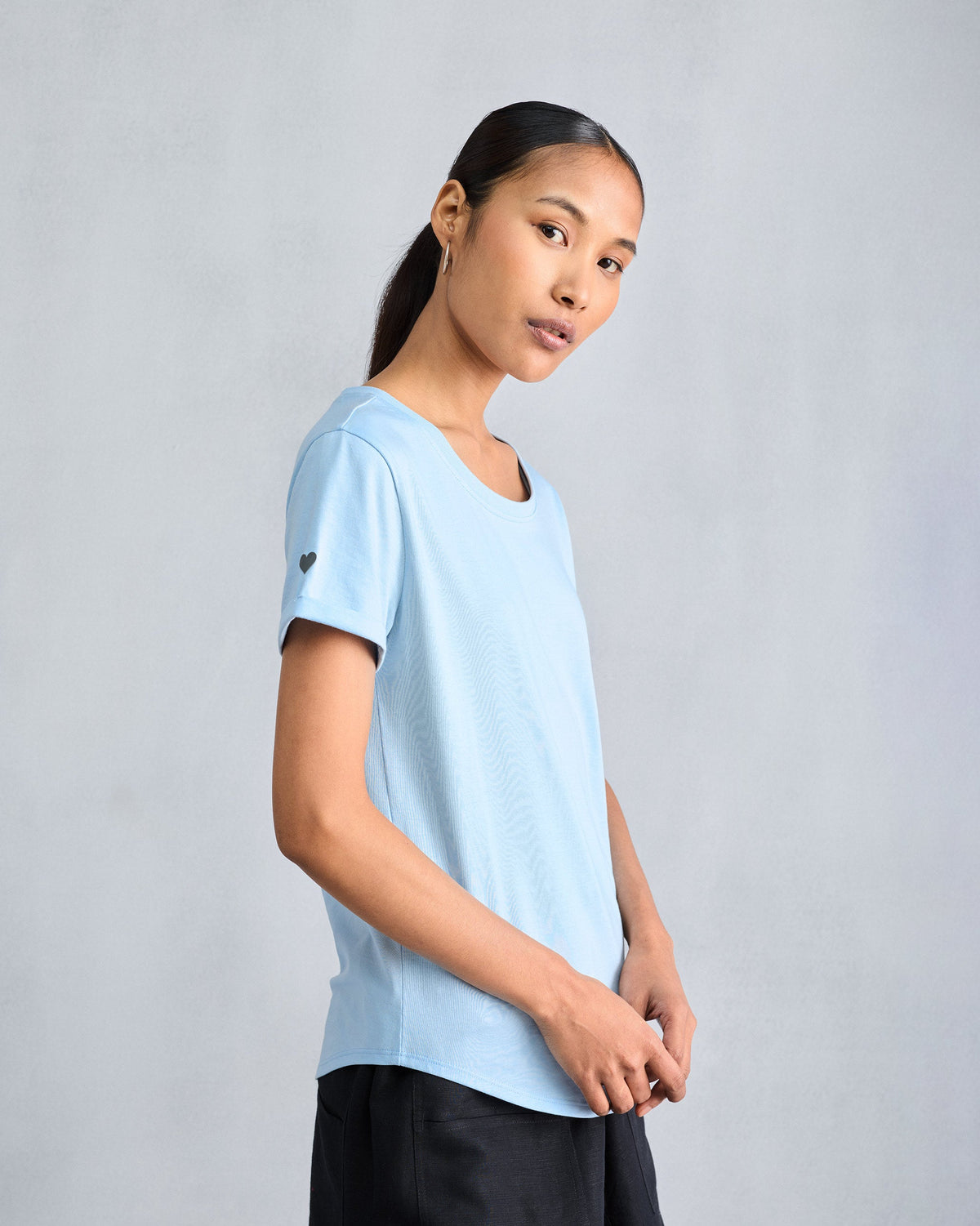 Three-quarter view of a light blue Basic t-shirt with a sleeve heart.