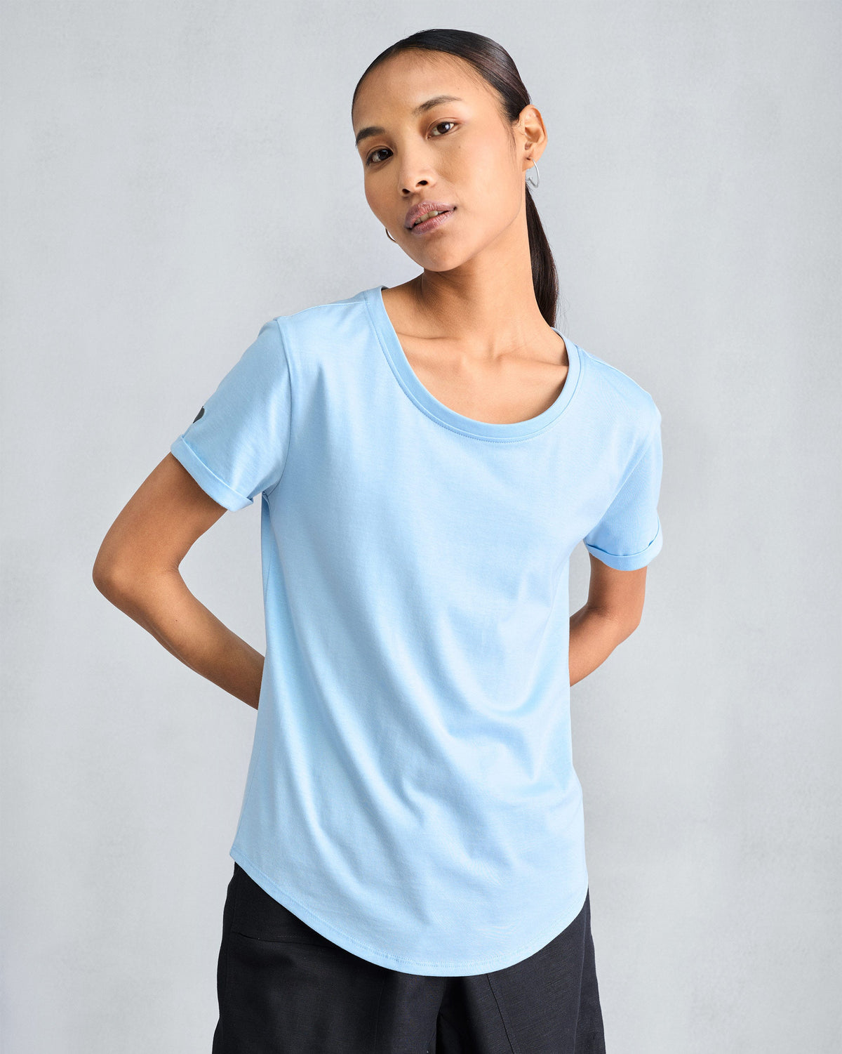 Person wearing a light blue Basic t-shirt with cuffed sleeves.