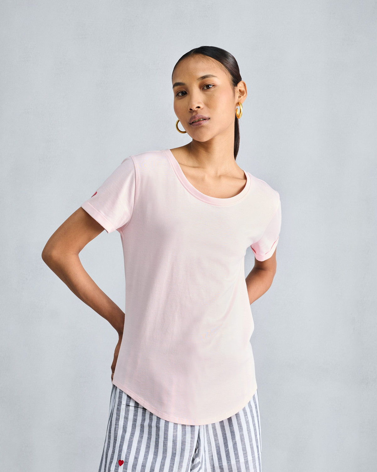 Side view of the Basic T-Shirt in blush pink worn by a person.