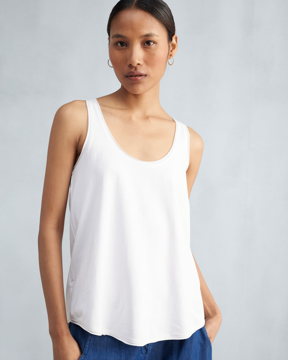 Person wearing a white Ukiyo tank with a scoop neckline.