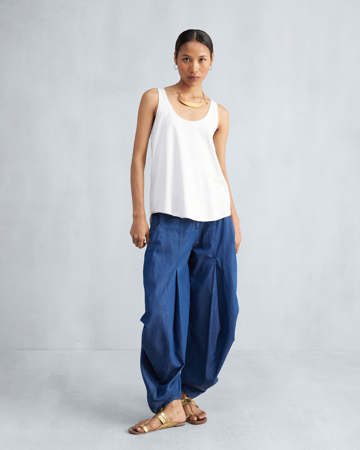 Person wearing a white Ukiyo racerback tank and wide blue pants.