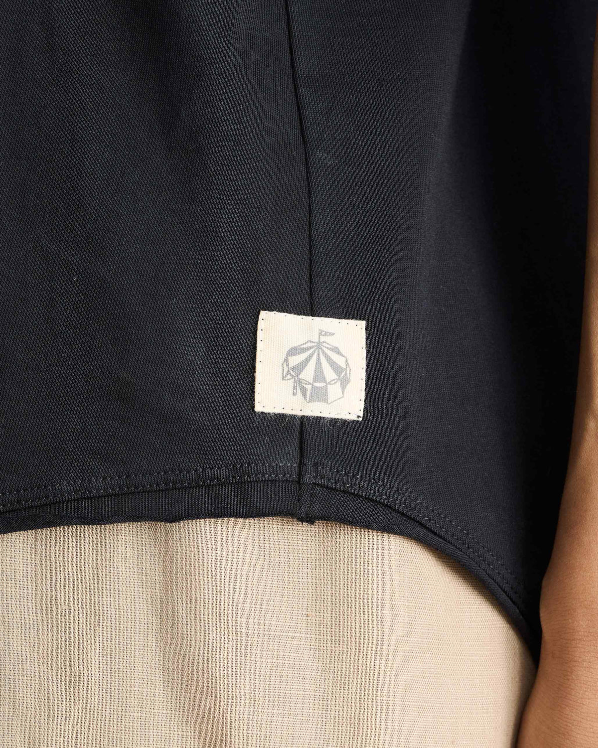 Close-up of a black Ukiyo tank hem with a small tent logo patch.