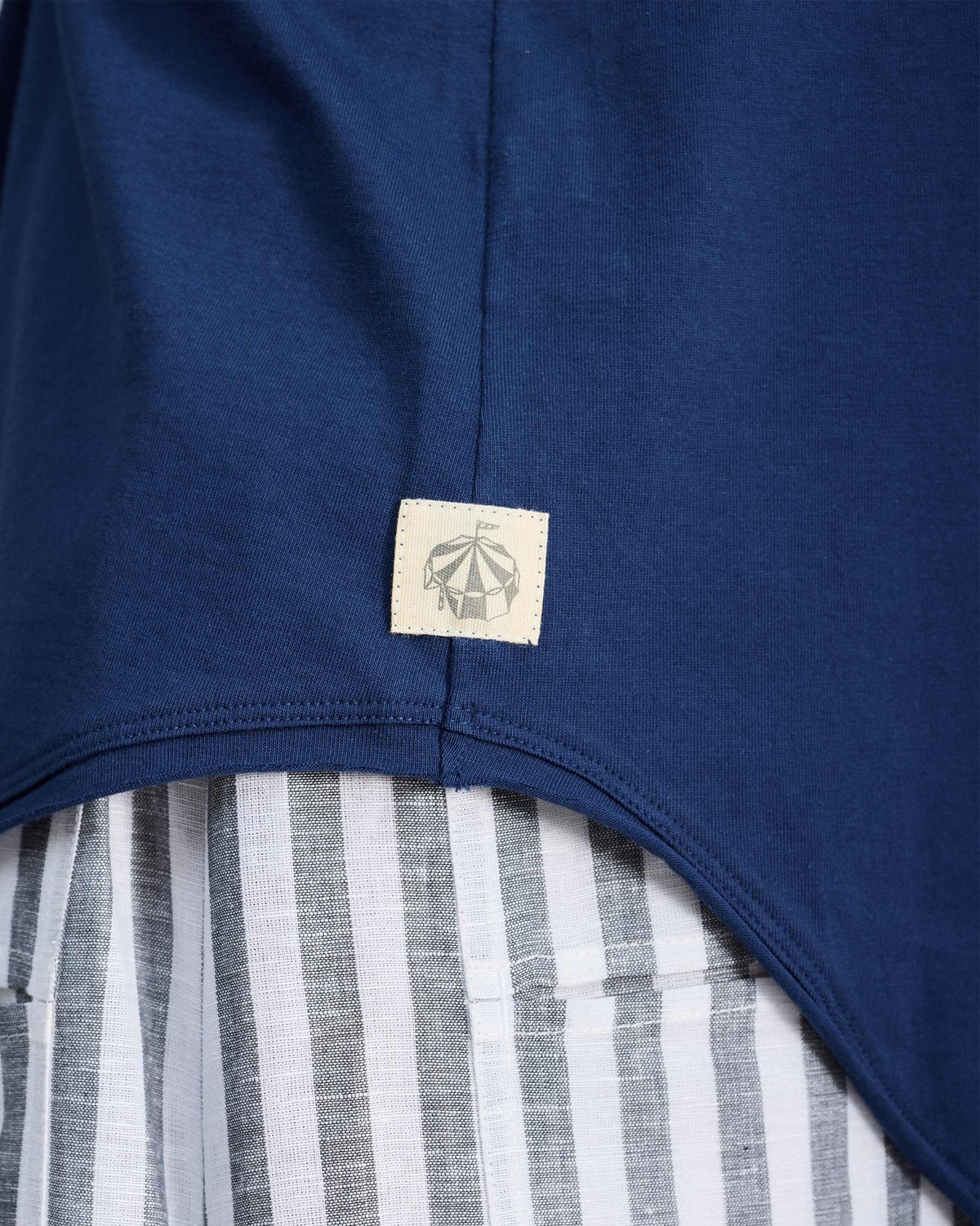 Close-up of a navy tank hem with a small circus tent patch.