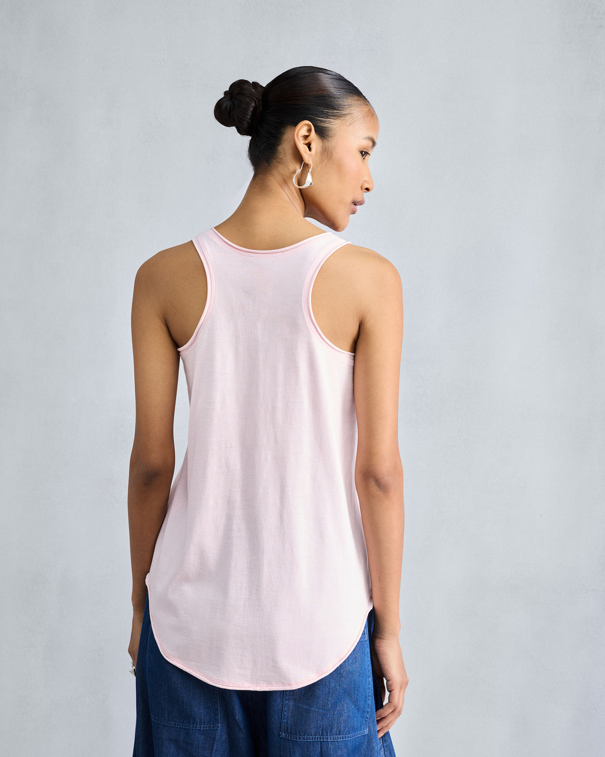 Back of a light pink Ukiyo racerback tank with a curved hem.