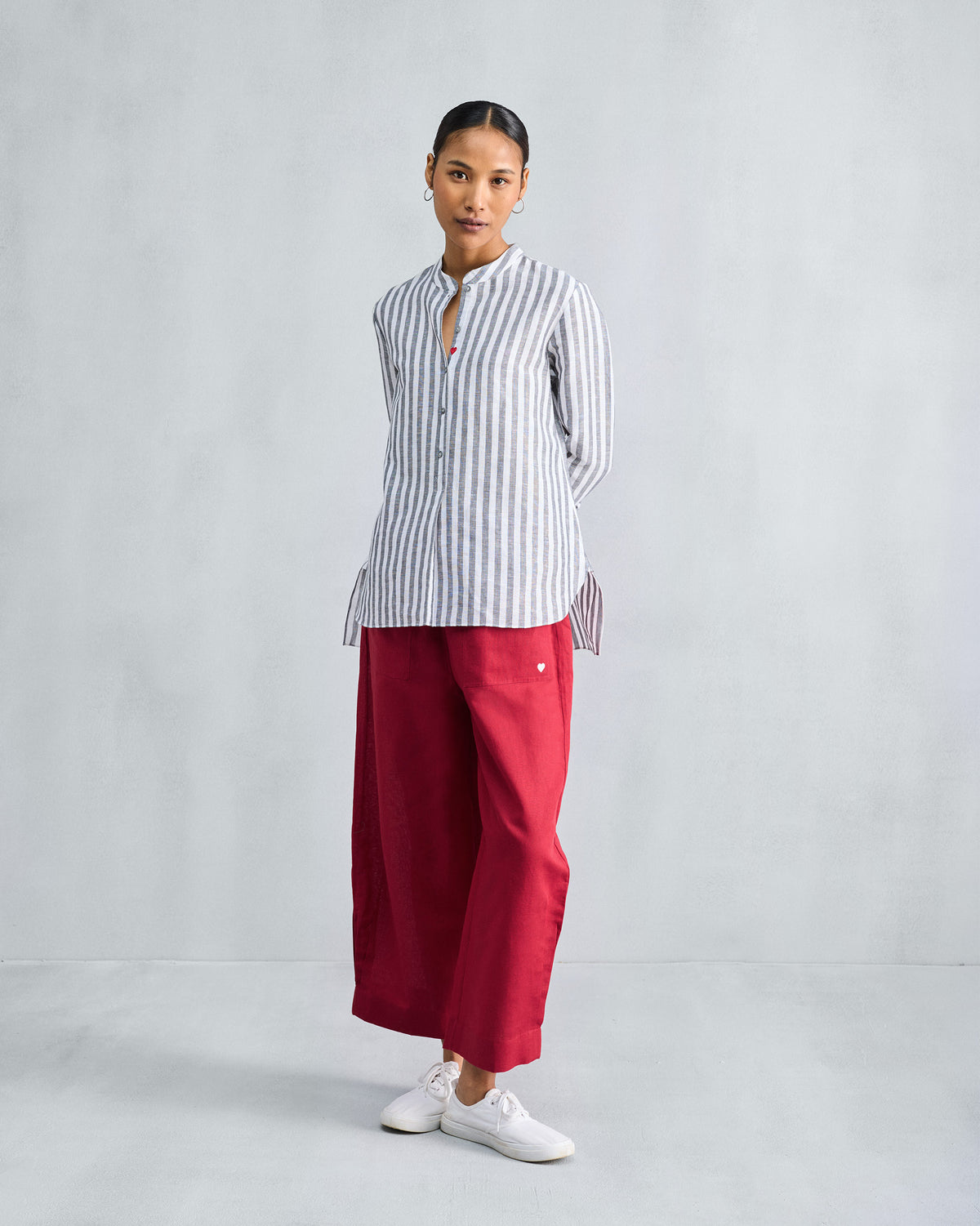 Person wearing a charcoal striped mandarin collar top with side slits.