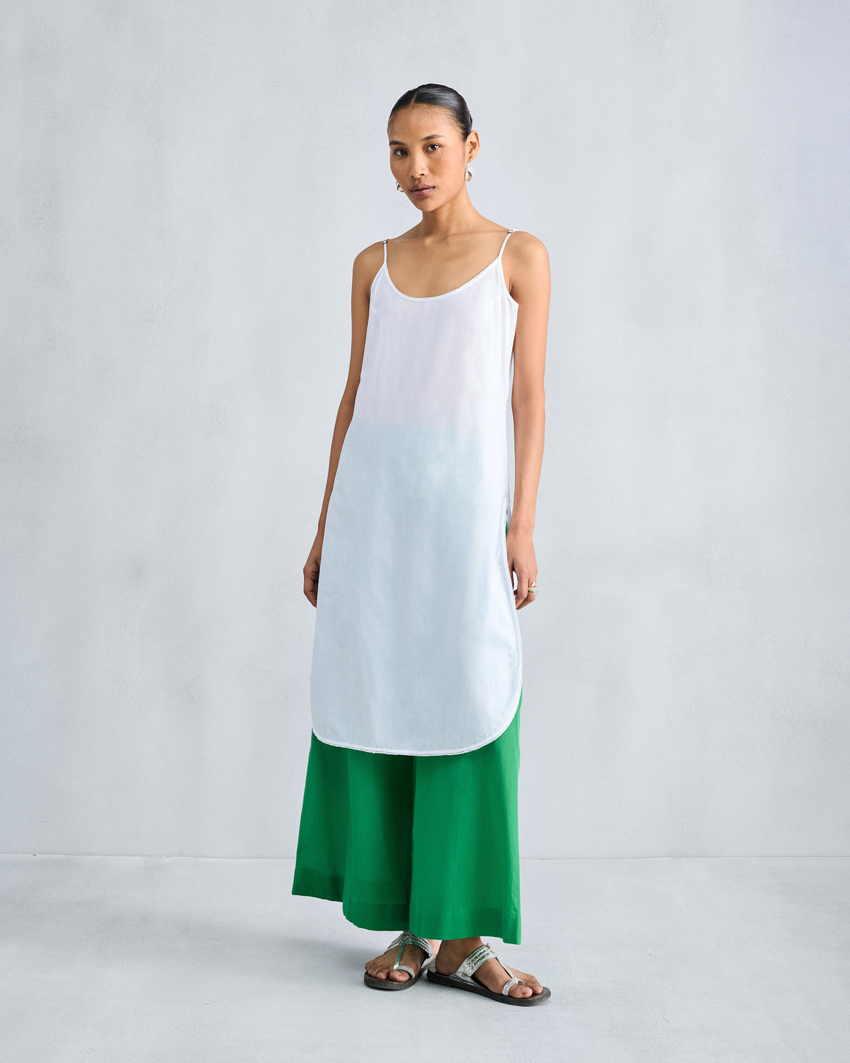 Person wearing bright green wide-leg pyjamas under a long white camisole.