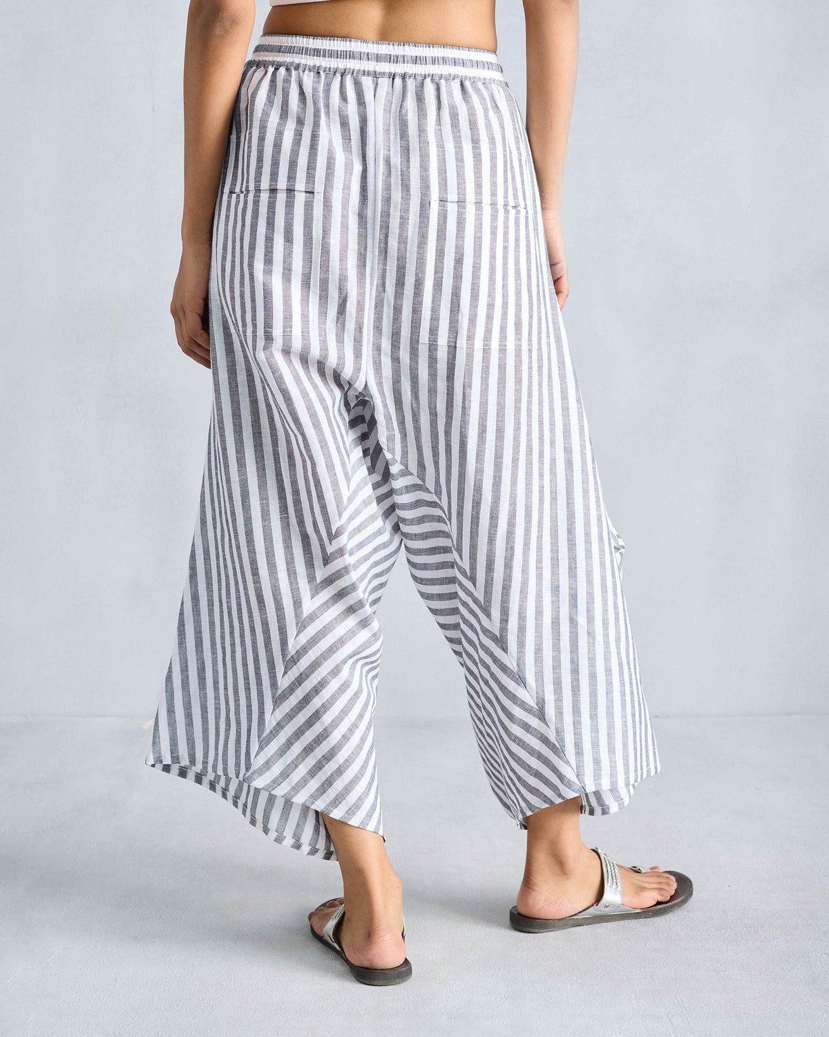 Back of charcoal and white striped Yoka Trousers with pointed hems.
