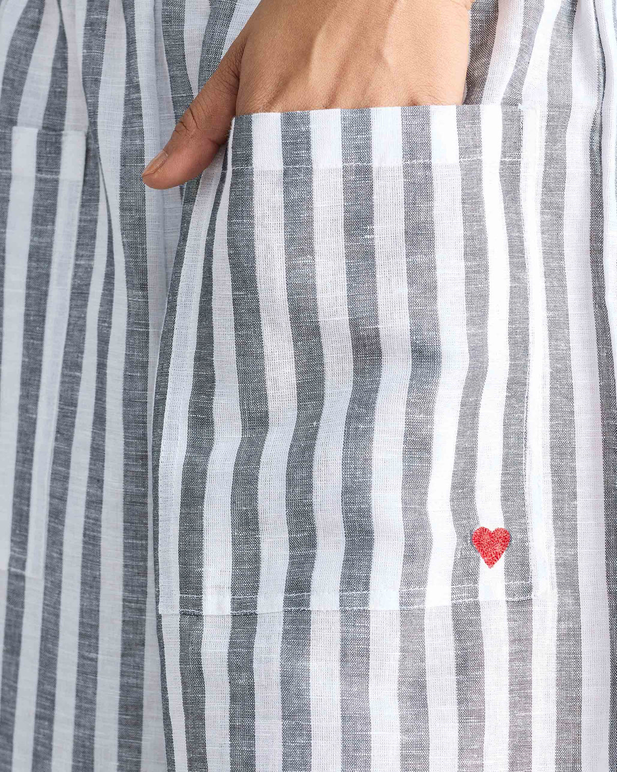 Close-up of striped Serene pants showing a patch pocket with a red embroidered heart.