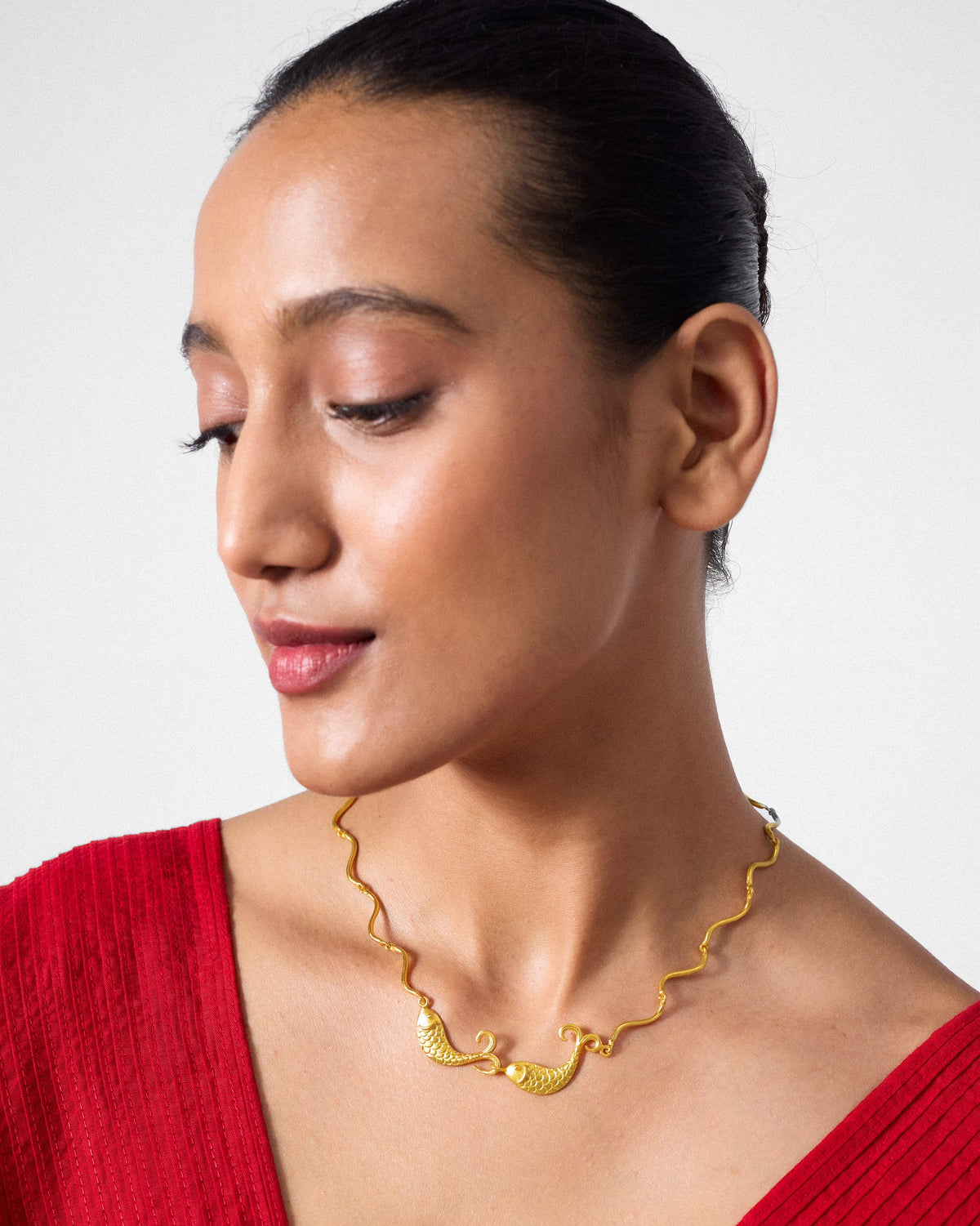 Gold Meen necklace with twin fish on a wavy chain.