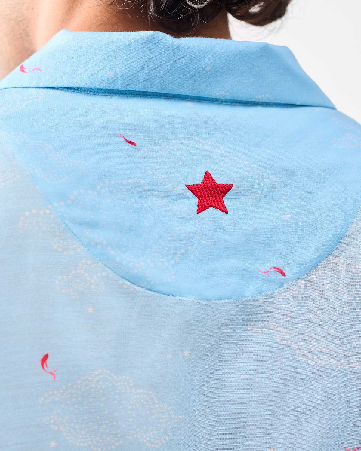 Close-up of the red embroidered star on the back of a light blue Mistari Shirt.