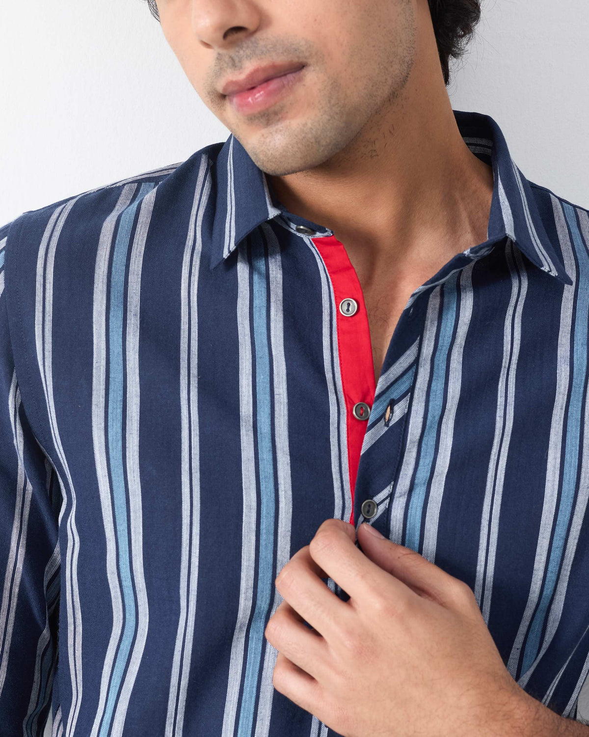 Close-up of the red placket lining on a blue and navy striped Comoros kurta.