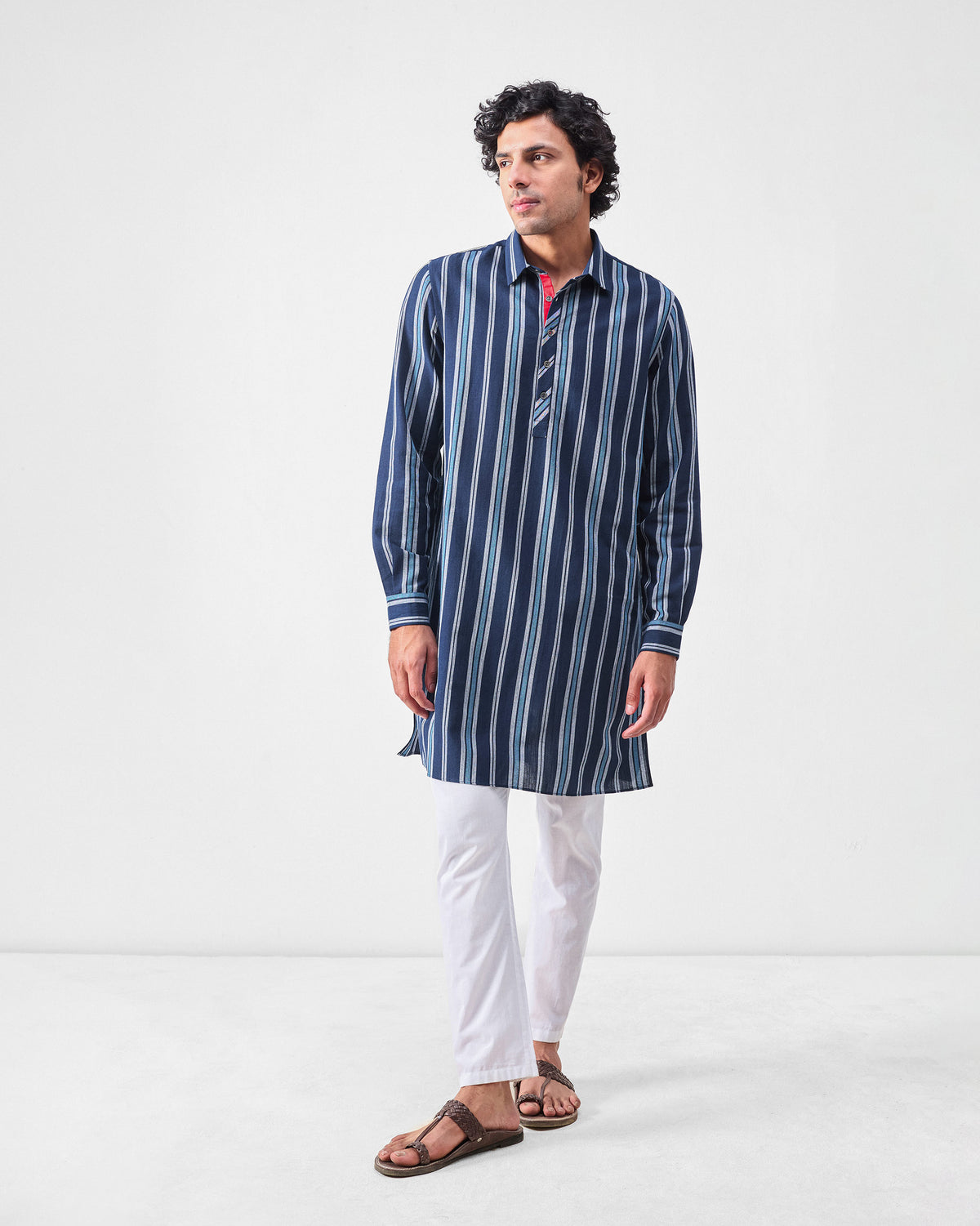 Person wearing a mid-thigh blue and navy striped Comoros kurta.