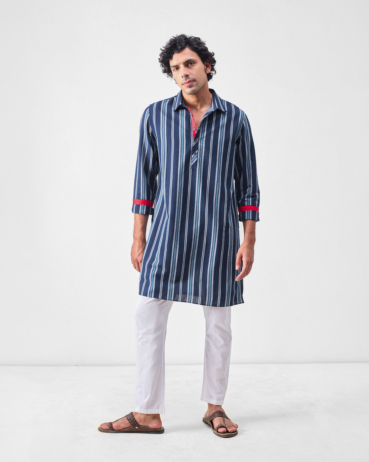 Person wearing a blue and navy striped Comoros kurta with red cuff bands.