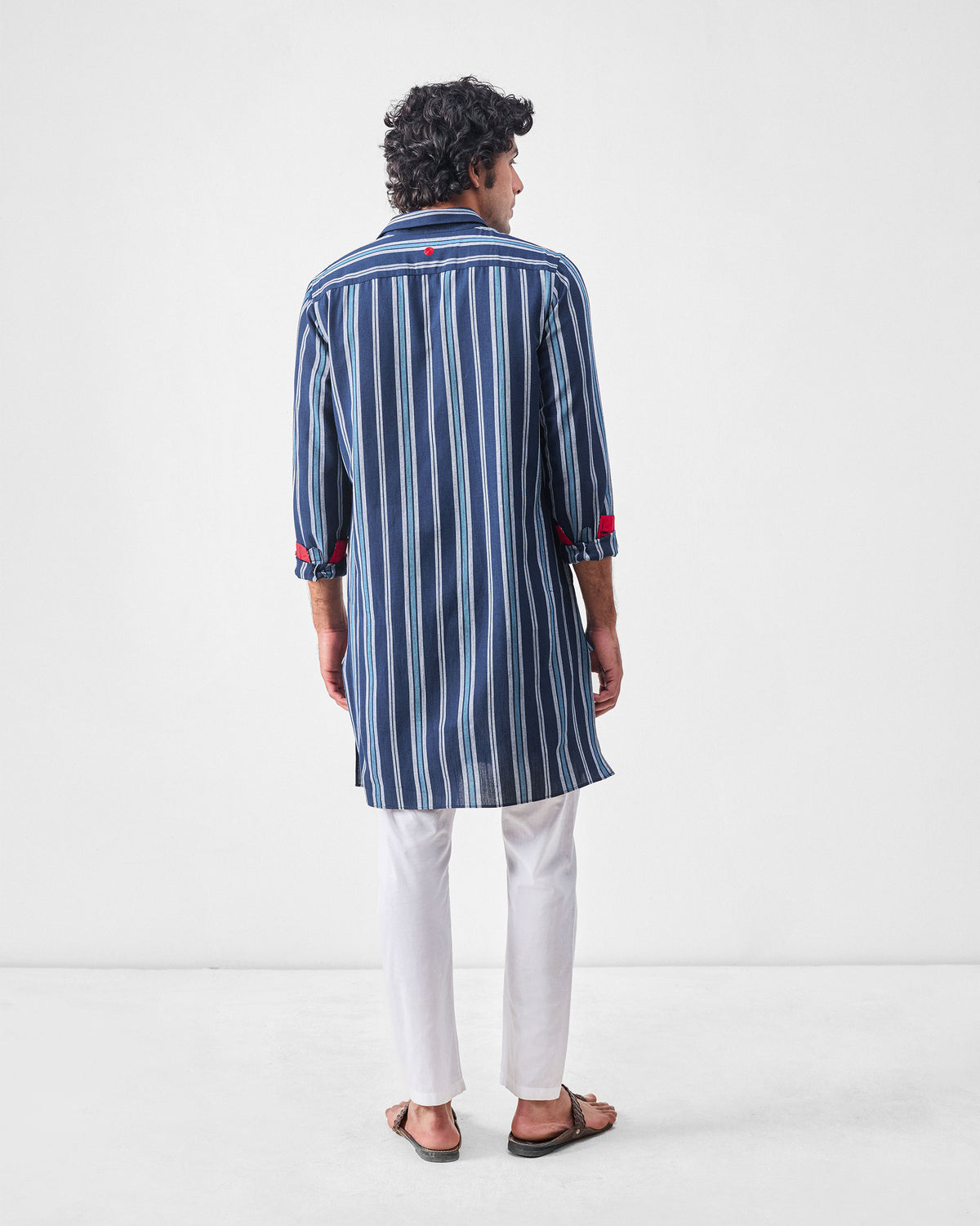 Back of a blue and navy striped Comoros kurta with red cuff lining.
