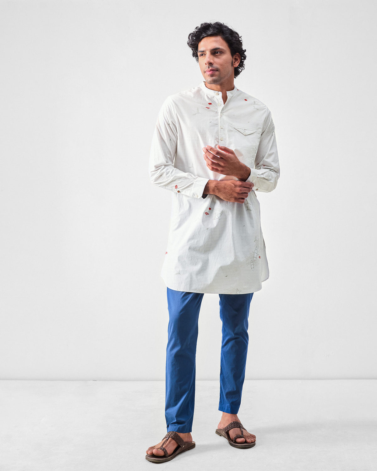 Person wearing a white Fort kurta with grey grid print and red motifs.